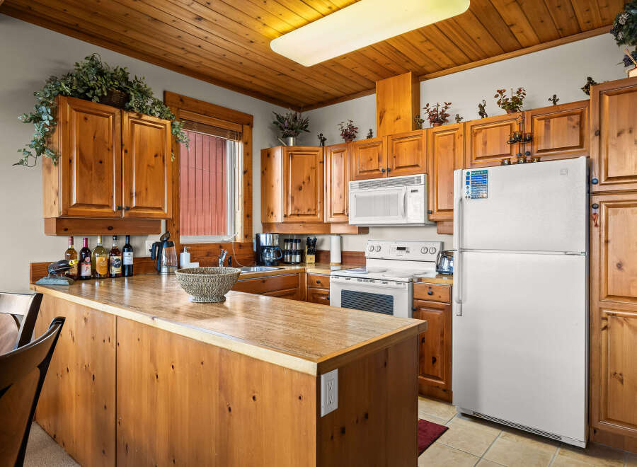 This charming kitchen features warm, knotty pine cabinetry and a spacious breakfast bar perfect for casual dining.