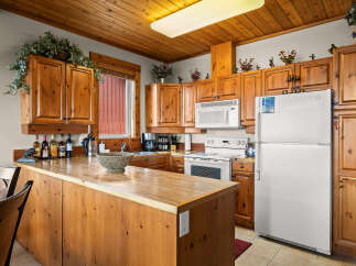 This charming kitchen features warm, knotty pine cabinetry and a spacious breakfast bar perfect for casual dining.