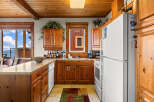 This charming kitchen features warm wooden cabinetry and countertops, complemented by a spacious window offering stunning mountain and sky views.