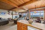 Experience breathtaking mountain views from this stunning living and dining area, featuring a cozy stone fireplace and a warm, wood-paneled ceiling.