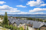 Discover this stunning mountain property featuring a row of charming townhomes with dark pitched roofs, nestled amidst lush evergreen trees.