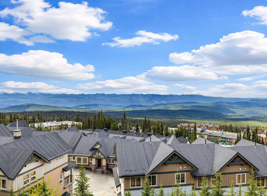 Discover this stunning mountain retreat featuring modern townhomes with dark pitched roofs and warm-toned exteriors.