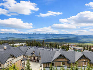 Discover this stunning mountain retreat featuring modern townhomes with dark pitched roofs and warm-toned exteriors.