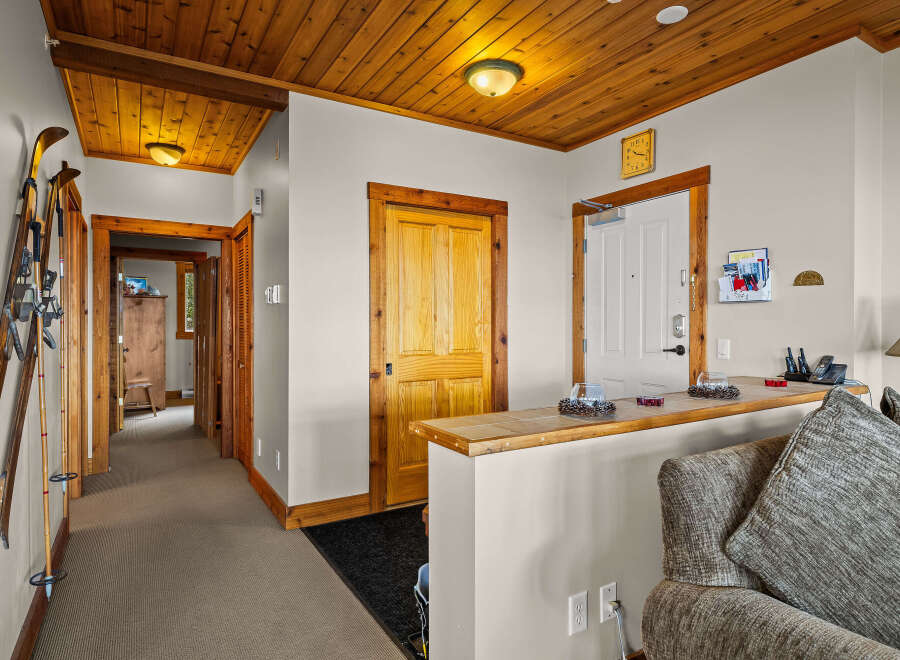 Step into a warm and inviting entryway featuring a charming wooden ceiling and a convenient ski rack, perfect for mountain enthusiasts.