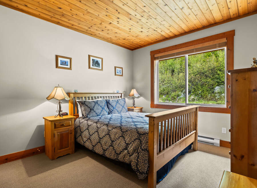 Experience cozy comfort in this charming bedroom, featuring a plush queen-size bed adorned with a beautiful blue and gold patterned comforter.