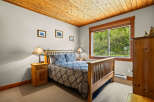 Experience cozy comfort in this charming bedroom, featuring a plush queen-size bed adorned with a beautiful blue and gold patterned comforter.