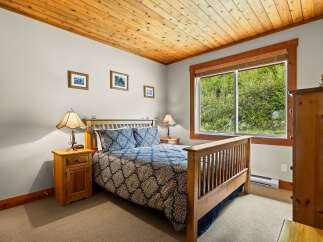 Experience cozy comfort in this charming bedroom, featuring a plush queen-size bed adorned with a beautiful blue and gold patterned comforter.