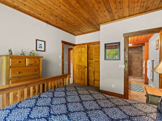 Experience rustic charm in this cozy bedroom featuring a wooden plank ceiling and a comfortable bed with a striking blue and white patterned comforter.