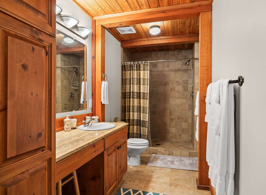 This rustic bathroom features warm wood accents and a spacious walk-in shower with tiled walls.