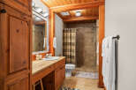 This rustic bathroom features warm wood accents and a spacious walk-in shower with tiled walls.