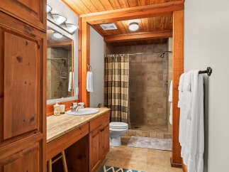 This rustic bathroom features warm wood accents and a spacious walk-in shower with tiled walls.
