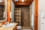 Experience rustic charm in this bathroom featuring a tiled walk-in shower with a patterned shower curtain and a wooden beam accent.