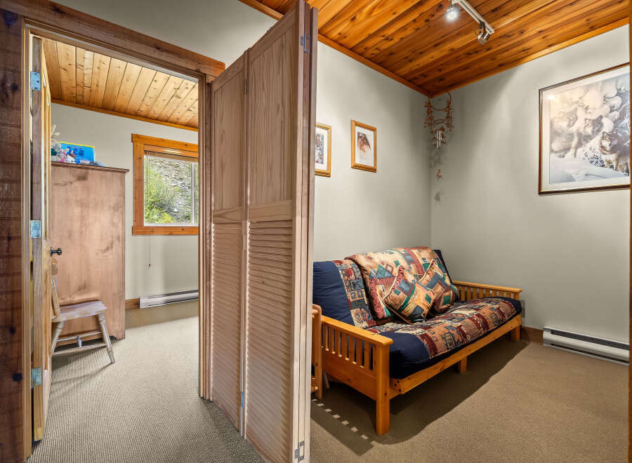 This charming room features a comfortable futon with a colorful, patterned comforter and throw pillows, perfect for relaxing.