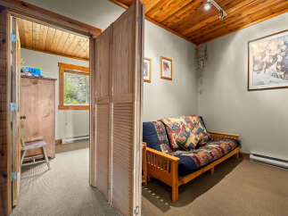 This charming room features a comfortable futon with a colorful, patterned comforter and throw pillows, perfect for relaxing.