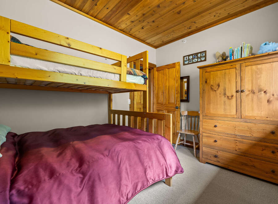 This charming bedroom features a space-saving bunk bed and a lower full-size bed, perfect for families or guests.