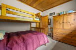 This charming bedroom features a space-saving bunk bed and a lower full-size bed, perfect for families or guests.