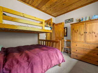 This charming bedroom features a space-saving bunk bed and a lower full-size bed, perfect for families or guests.