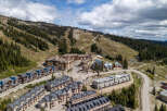 Discover this stunning mountain resort property featuring a collection of modern townhomes and condominiums nestled against a backdrop of ski slopes and lush pine forests.
