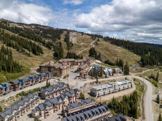 Discover this stunning mountain resort property featuring a collection of modern townhomes and condominiums nestled against a backdrop of ski slopes and lush pine forests.