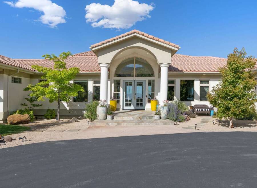This stunning home features a grand entrance with arched portico, flanked by stately columns and leading to elegant double doors.