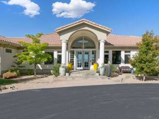 This stunning home features a grand entrance with arched portico, flanked by stately columns and leading to elegant double doors.
