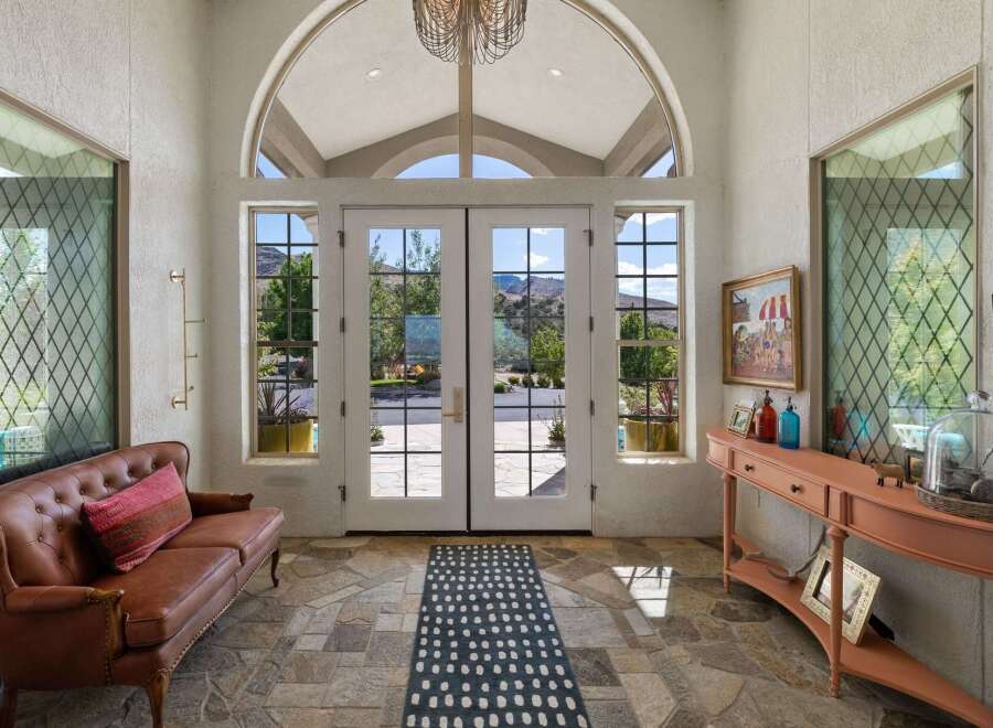 Step into this grand entryway featuring a stunning arched window and double doors that open to breathtaking mountain views.