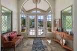Step into this grand entryway featuring a stunning arched window and double doors that open to breathtaking mountain views.