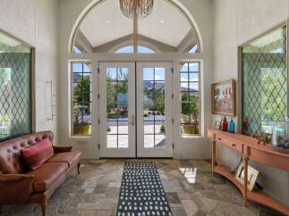 Step into this grand entryway featuring a stunning arched window and double doors that open to breathtaking mountain views.