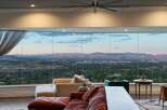 Experience breathtaking panoramic views from this stunning living room, featuring expansive floor-to-ceiling windows that showcase a sprawling cityscape and majestic mountain range.