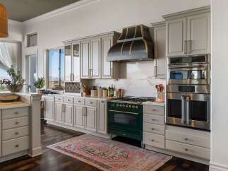 Experience culinary excellence in this stunning kitchen, featuring a professional-grade emerald green range complemented by a striking custom range hood.