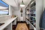 Discover ample storage in this spacious pantry, featuring floor-to-ceiling shelving equipped with convenient black woven baskets.