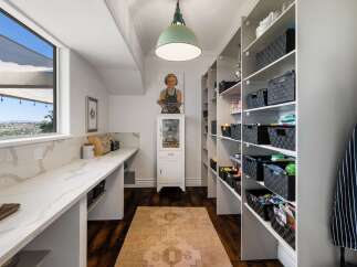 Discover ample storage in this spacious pantry, featuring floor-to-ceiling shelving equipped with convenient black woven baskets.