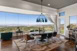 Experience breathtaking panoramic views from this stunning dining room, featuring a wall of expansive windows that showcase a picturesque landscape.