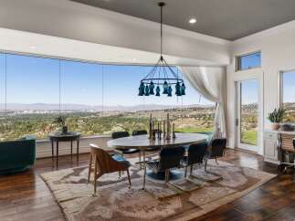 Experience breathtaking panoramic views from this stunning dining room, featuring a wall of expansive windows that showcase a picturesque landscape.