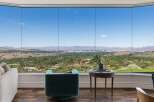 Experience breathtaking panoramic views from this stunning property, featuring expansive floor-to-ceiling windows that showcase a vibrant cityscape and rolling hills.