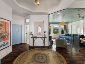 Step into this stunning entryway featuring a bold vintage poster and a light blue door, leading to a living area with breathtaking mountain views through expansive glass walls.
