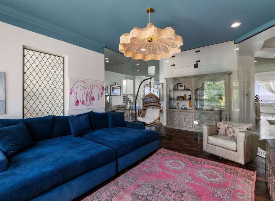 Experience luxurious living in this stunning home, featuring a vibrant blue sectional sofa complemented by a striking pink Persian rug.