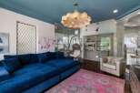 Experience luxurious living in this stunning home, featuring a vibrant blue sectional sofa complemented by a striking pink Persian rug.