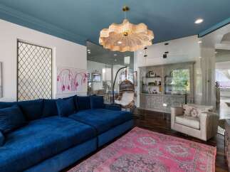Experience luxurious living in this stunning home, featuring a vibrant blue sectional sofa complemented by a striking pink Persian rug.