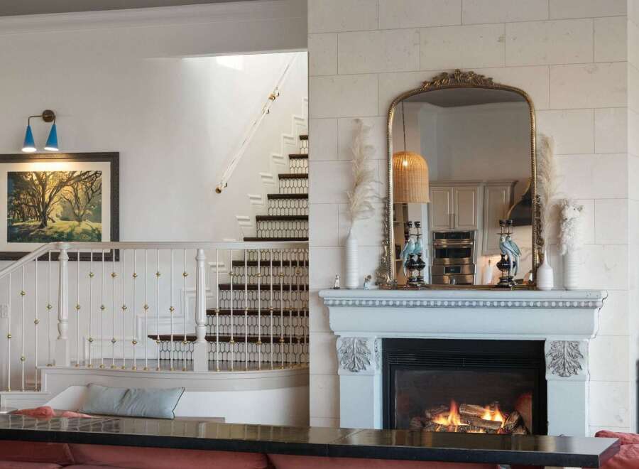 Experience elegance and warmth in this stunning living space, featuring a grand staircase with intricate railings and a cozy fireplace as the focal point.