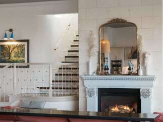 Experience elegance and warmth in this stunning living space, featuring a grand staircase with intricate railings and a cozy fireplace as the focal point.