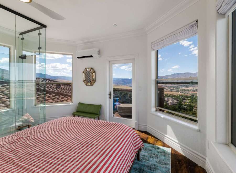 Experience breathtaking panoramic views from this stunning bedroom, featuring expansive windows that showcase the picturesque landscape.