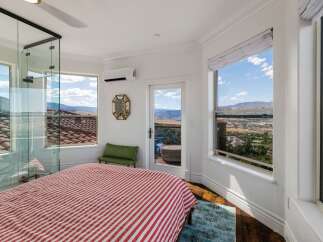 Experience breathtaking panoramic views from this stunning bedroom, featuring expansive windows that showcase the picturesque landscape.