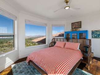 Experience breathtaking panoramic views from this stunning bedroom, featuring large windows that showcase the picturesque landscape and distant city lights.