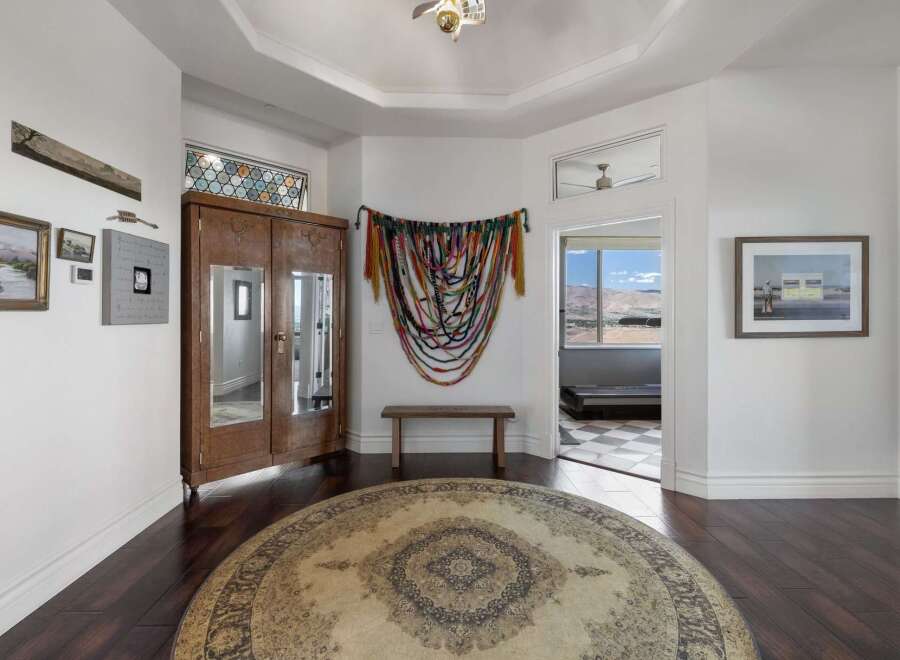 Step into this inviting entryway featuring a large round rug and a beautiful wooden armoire with mirrored doors.