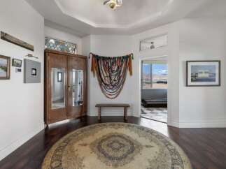 Step into this inviting entryway featuring a large round rug and a beautiful wooden armoire with mirrored doors.