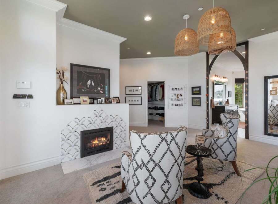 Experience luxury living with this stunning master suite, featuring a cozy fireplace with unique tile accents and a spacious walk-in closet.
