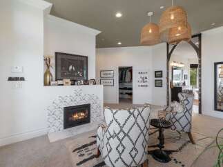 Experience luxury living with this stunning master suite, featuring a cozy fireplace with unique tile accents and a spacious walk-in closet.