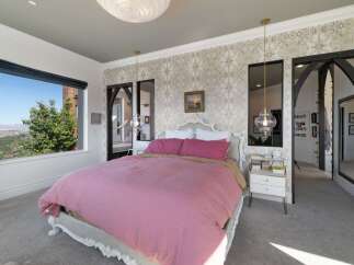 Experience luxury in this stunning bedroom featuring a plush pink duvet and a decorative white headboard.