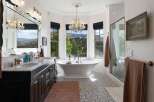 Indulge in luxury with this stunning bathroom featuring a freestanding soaking tub positioned perfectly to enjoy breathtaking mountain views through large bay windows.